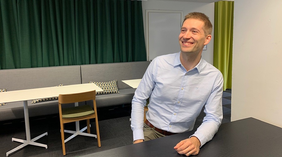 Kuva digitaalisten palveluiden asiantuntija Okko Rostedtista istumassa ja nauramassa pöydän ääressä
