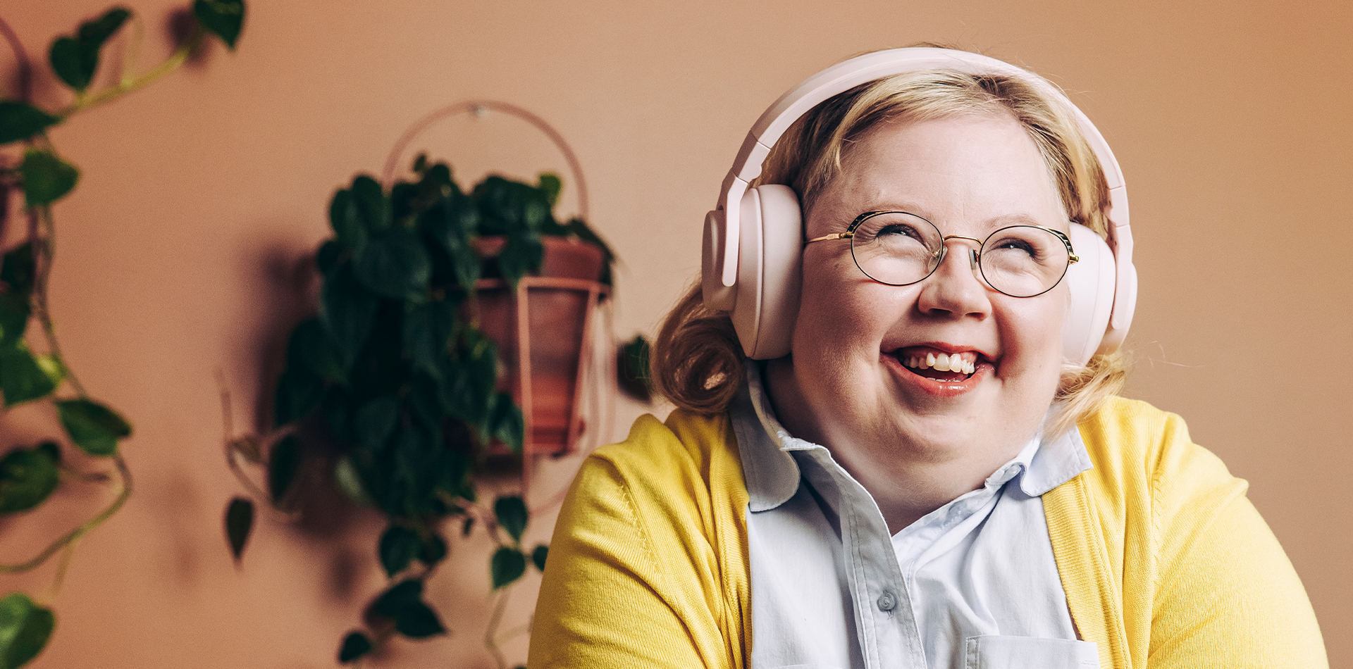 Kuvituskuva: hymyilevä nuori nainen kuulokkeet päässä.